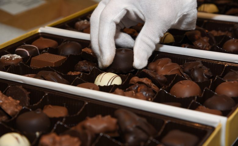 gloved hand putting chocolate in a wrapper