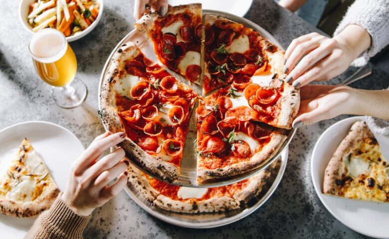 aerial view of dining table and hands reaching for a pizza